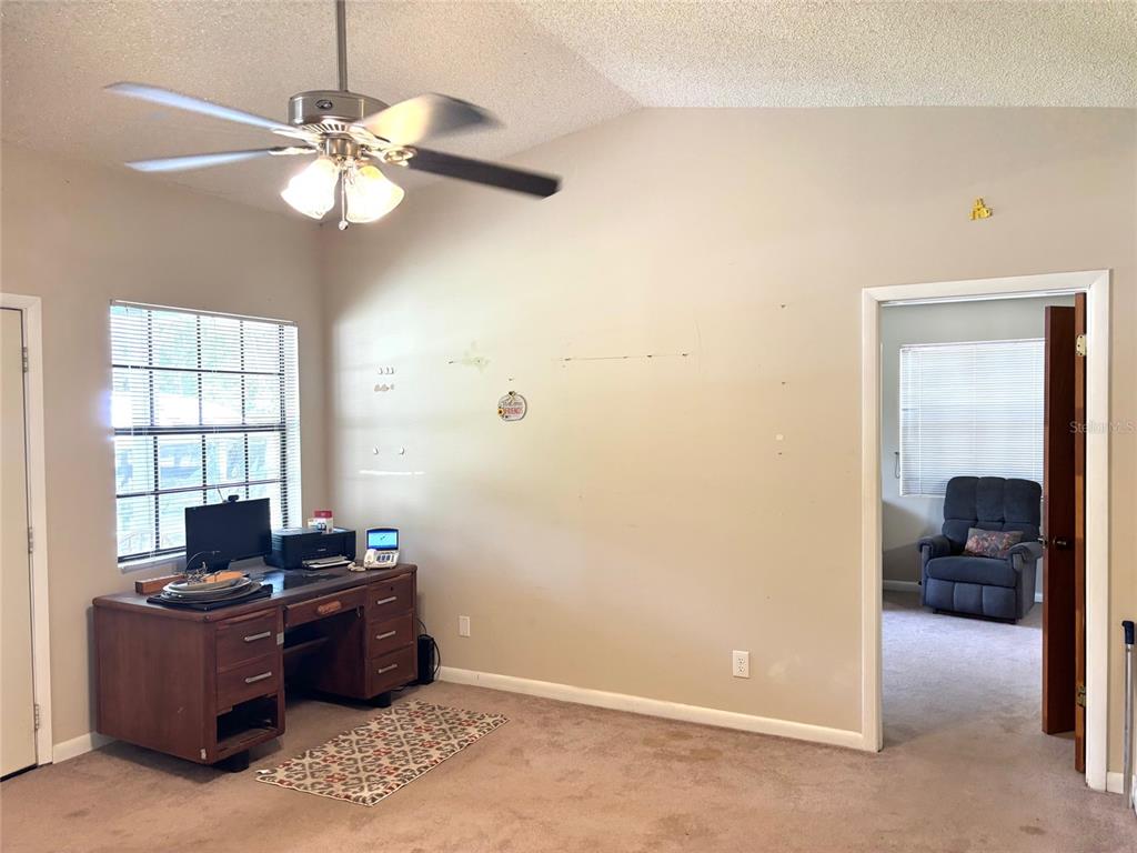 A room with beige walls, carpeted flooring, a ceiling fan, a desk, and a doorway — 333 RIVIERA DRIVE, CRESCENT CITY, FL
