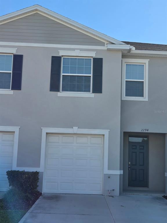 A two-story townhouse exterior features a single-car garage, a front door, and gray siding — 2294 TAY WES DRIVE, ST CLOUD, FL