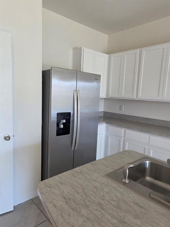 A kitchen features white cabinets, stainless steel appliances, and a laminate countertop island — 2294 TAY WES DRIVE, ST CLOUD, FL