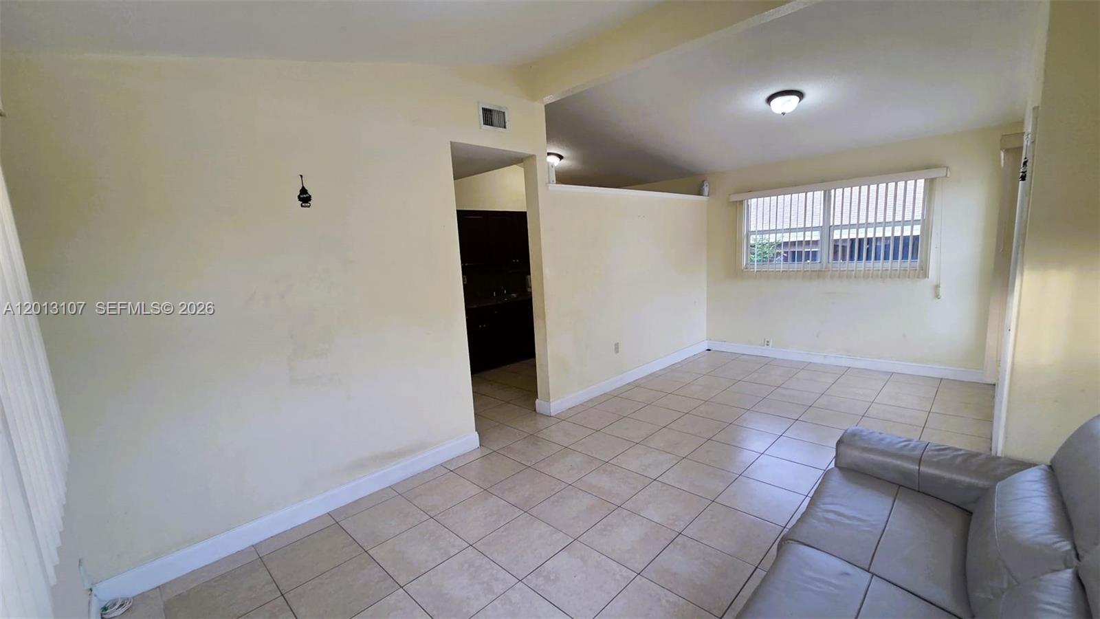 A living room with light-colored tile flooring, pale yellow walls, and a partial wall divider — 2335 NW 55th St, Miami FL 33142, MIAMI, FL