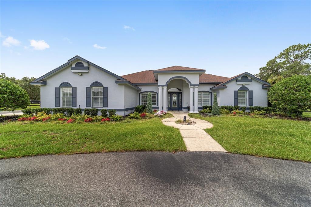 A single-story house with a gray exterior, arched windows, and a paved walkway — 6208 NW 12TH STREET, OCALA, FL