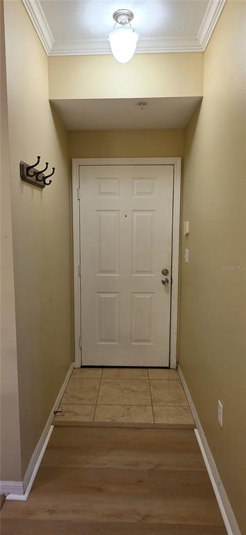 An entryway features a white door, a light fixture, coat hooks, and tiled and wood flooring — 5618 PINNACLE HEIGHTS CIRCLE UNIT 211, TAMPA, FL