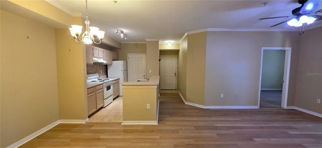 An open-concept kitchen with light wood cabinets and a breakfast bar overlooks a living area — 5618 PINNACLE HEIGHTS CIRCLE UNIT 211, TAMPA, FL
