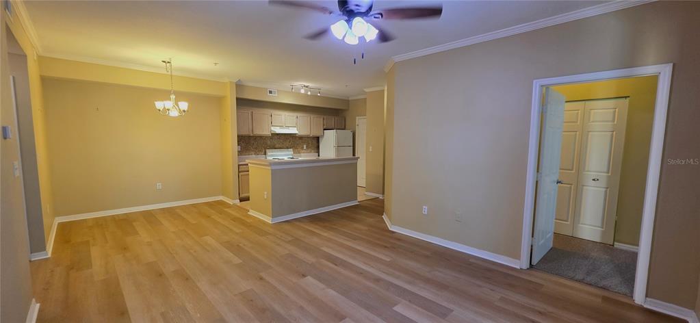 An open-concept living and dining area features light wood-look flooring and a kitchen island — 5618 PINNACLE HEIGHTS CIRCLE UNIT 211, TAMPA, FL