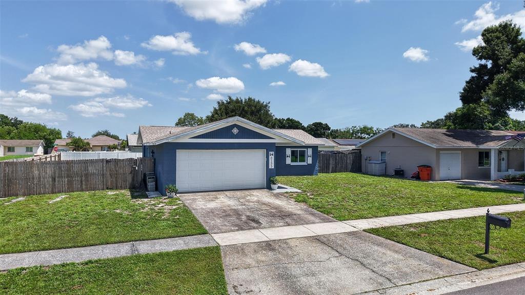 A blue single-story house with a white garage door and a concrete driveway — 8153 CANDLEWOODE DRIVE, LARGO, FL