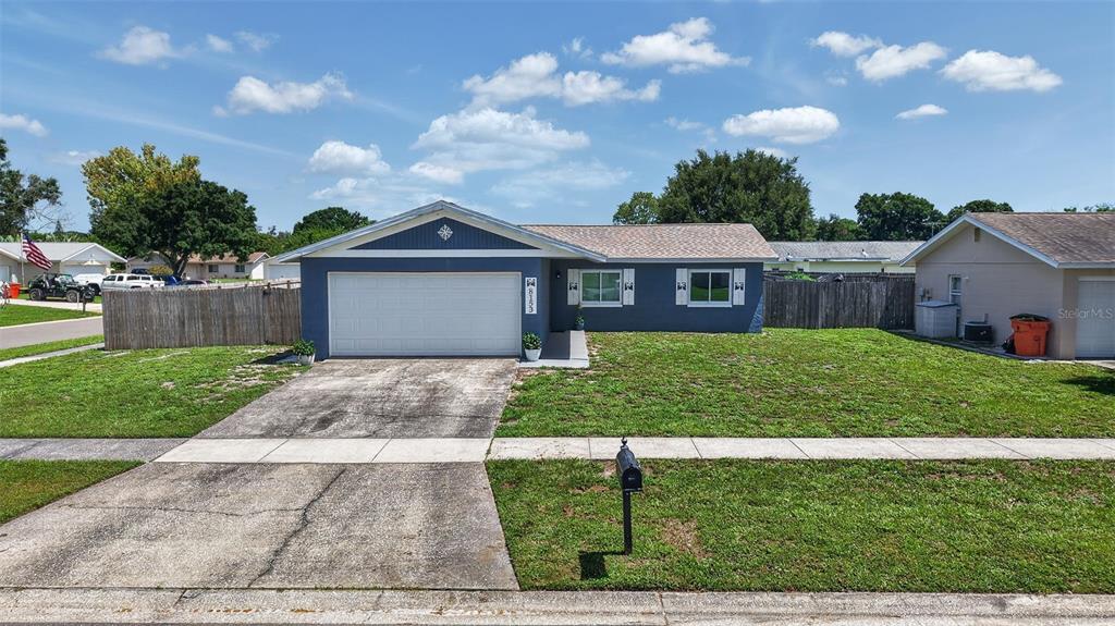 A blue single-story house features a two-car garage, a concrete driveway, and a front lawn — 8153 CANDLEWOODE DRIVE, LARGO, FL