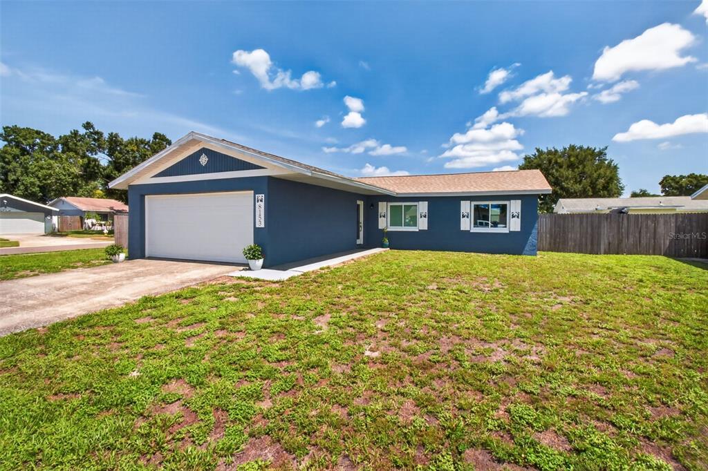 A single-story blue house with a two-car garage and a large front lawn — 8153 CANDLEWOODE DRIVE, LARGO, FL