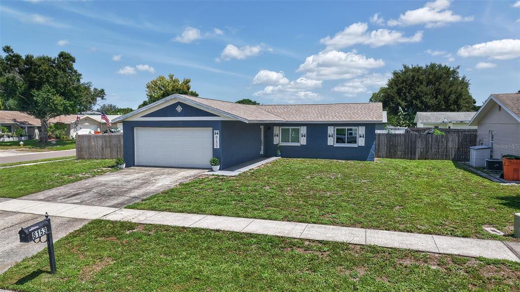 A blue single-story house with a white garage door and a front lawn — 8153 CANDLEWOODE DRIVE, LARGO, FL