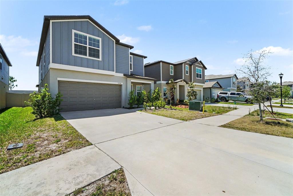 A two-story house with blue siding and a concrete driveway under a clear sky — 35194 ACKLEY TRACE, ZEPHYRHILLS, FL