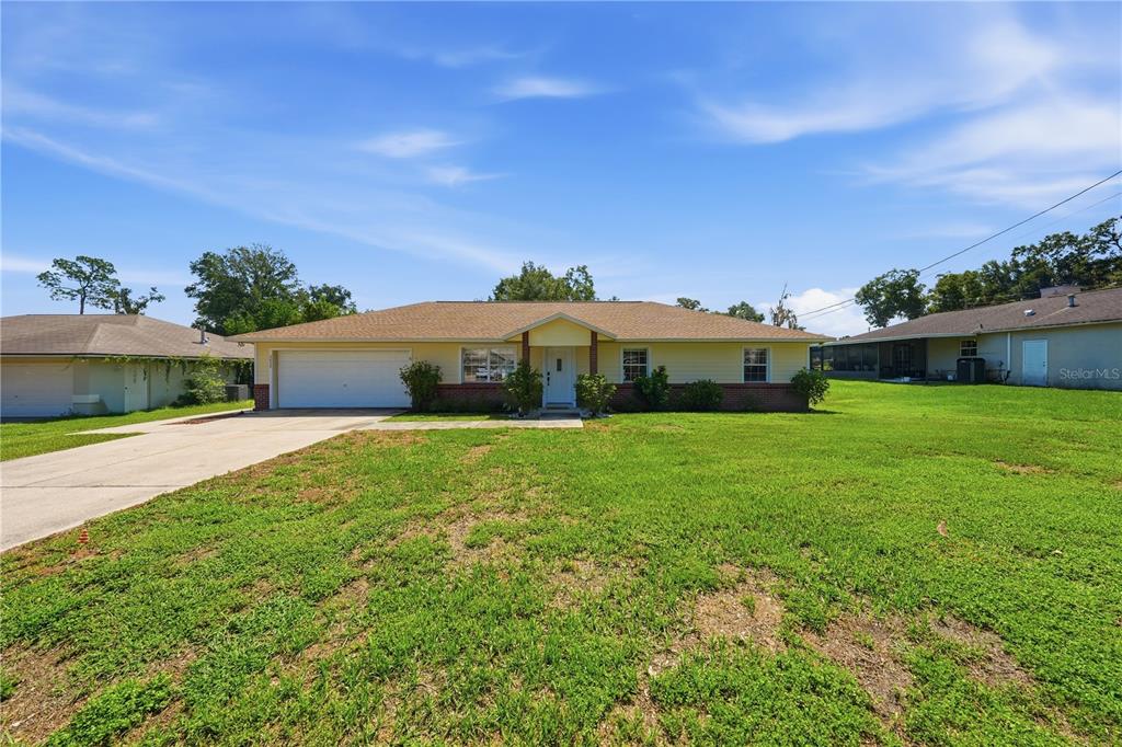 A single-story yellow house with a two-car garage and a large front lawn — 3835 NE 13TH AVENUE, OCALA, FL