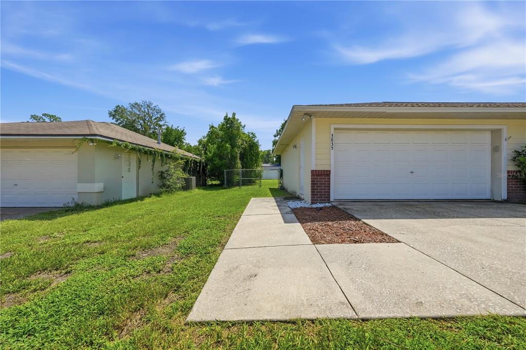 A view of two adjacent residential garages with a concrete driveway and lawn — 3835 NE 13TH AVENUE, OCALA, FL