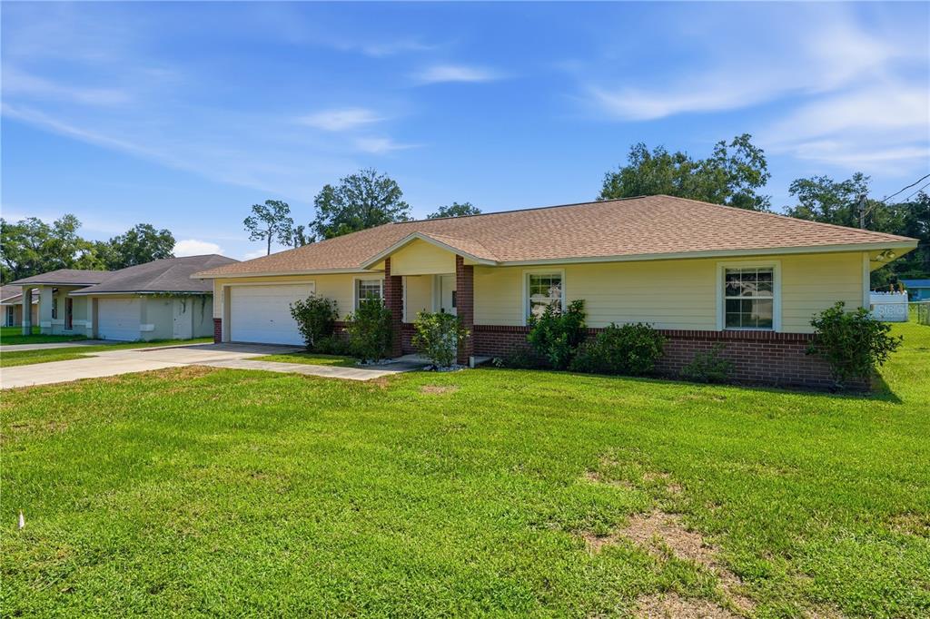 A single-story house with yellow siding, a brick base, and a two-car garage — 3835 NE 13TH AVENUE, OCALA, FL