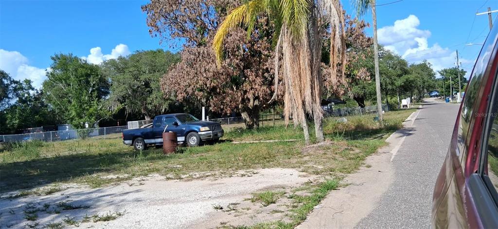 A blue pickup truck is parked on a grassy lot next to a paved road — 1110 GRAND AVENUE, SEBRING, FL