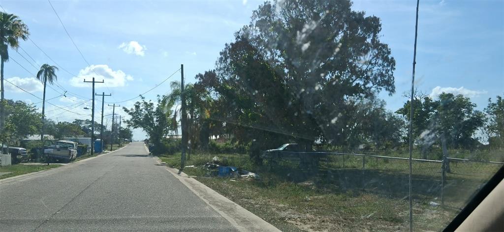 A paved residential street lined with utility poles, trees, and a chain-link fence — 1110 GRAND AVENUE, SEBRING, FL