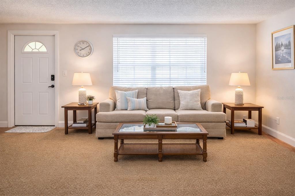 A living room features a beige sofa, two side tables with lamps, and a coffee table — 5008 27TH AVENUE W, BRADENTON, FL