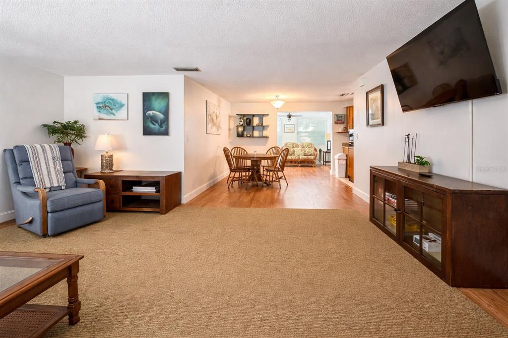A living room with carpet, a blue recliner, and a dining area in the background — 5008 27TH AVENUE W, BRADENTON, FL