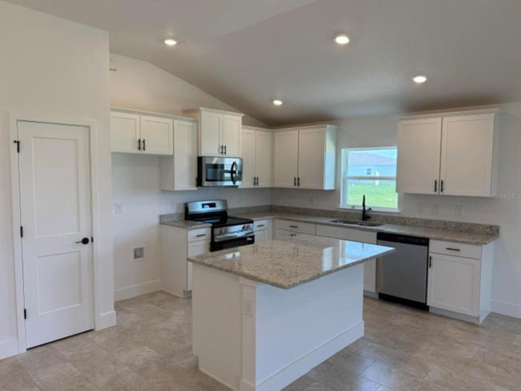 A kitchen with white cabinets, granite countertops, a center island, and stainless steel appliances — 2397 NW 23RD AVENUE, OCALA, FL