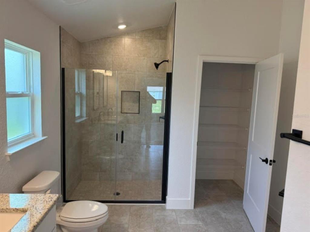 A bathroom features a tiled walk-in shower with a glass door and an adjacent closet — 2397 NW 23RD AVENUE, OCALA, FL