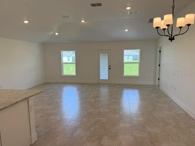 An open-concept living area features tile flooring, a chandelier, and a glass-paneled exterior door — 2397 NW 23RD AVENUE, OCALA, FL