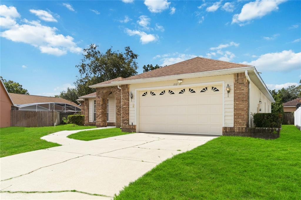 A single-story house with a beige exterior, brick accents, and a two-car garage — 1572 HUNTERS STAND RUN, OVIEDO, FL