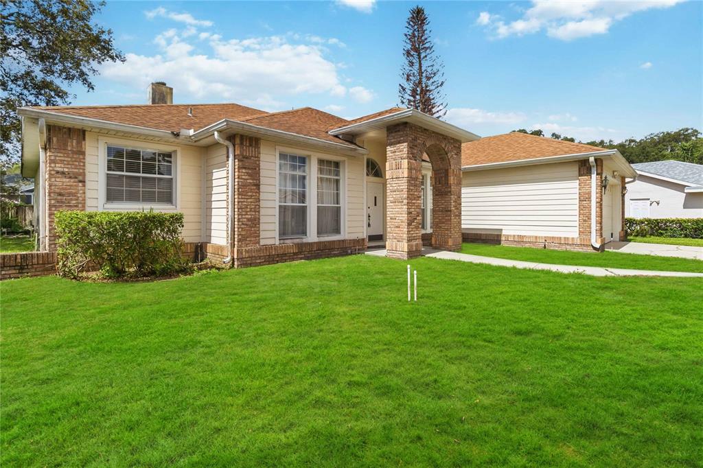 A single-story house with a brick and siding exterior, a front archway, and a lawn — 1572 HUNTERS STAND RUN, OVIEDO, FL