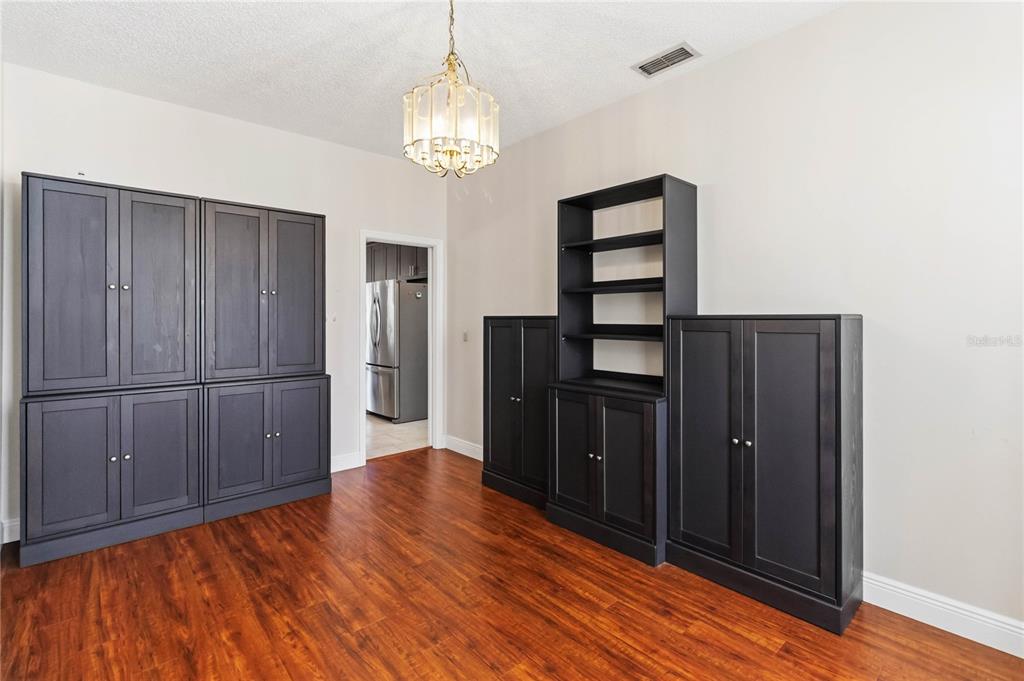 A dining room features dark cabinetry, wood-look flooring, and a central chandelier — 1572 HUNTERS STAND RUN, OVIEDO, FL