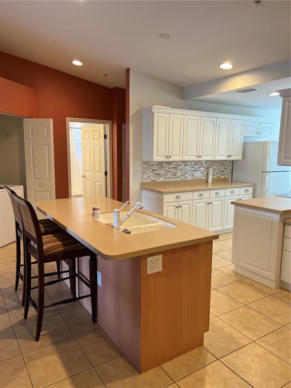 A kitchen features a wooden island with a sink, white cabinets, and tiled flooring — 7060 STRAND CIRCLE UNIT 7060, BRADENTON, FL