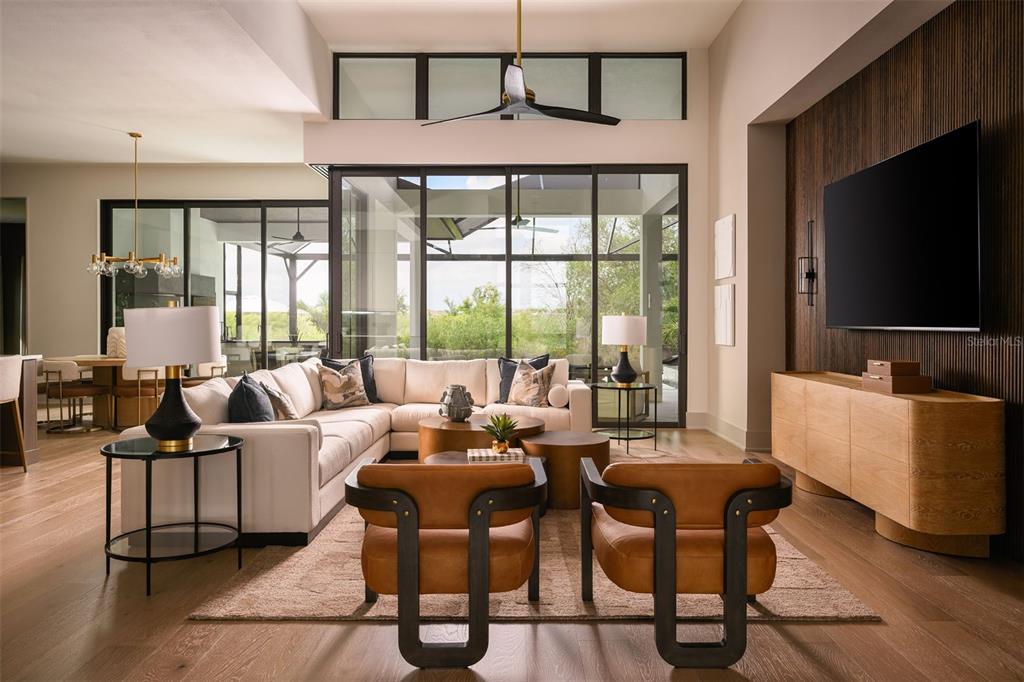 A modern living room features a sectional sofa, two leather chairs, and large glass doors — 263 CRYSTAL WATERS DRIVE, SARASOTA, FL