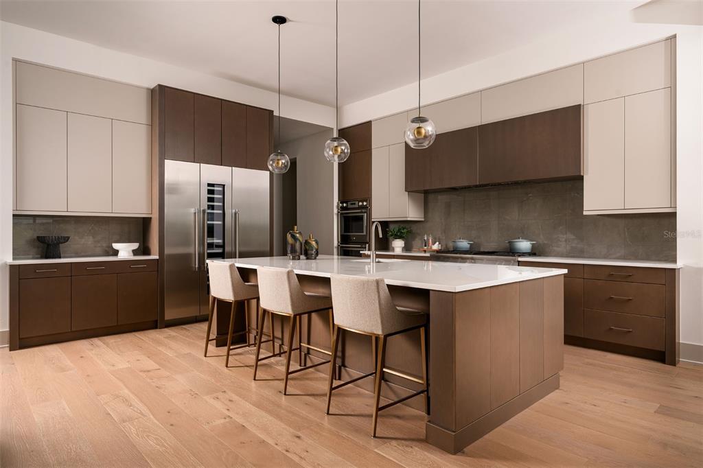 A modern kitchen features two-toned cabinetry, a large white island with barstools, and wood flooring — 263 CRYSTAL WATERS DRIVE, SARASOTA, FL