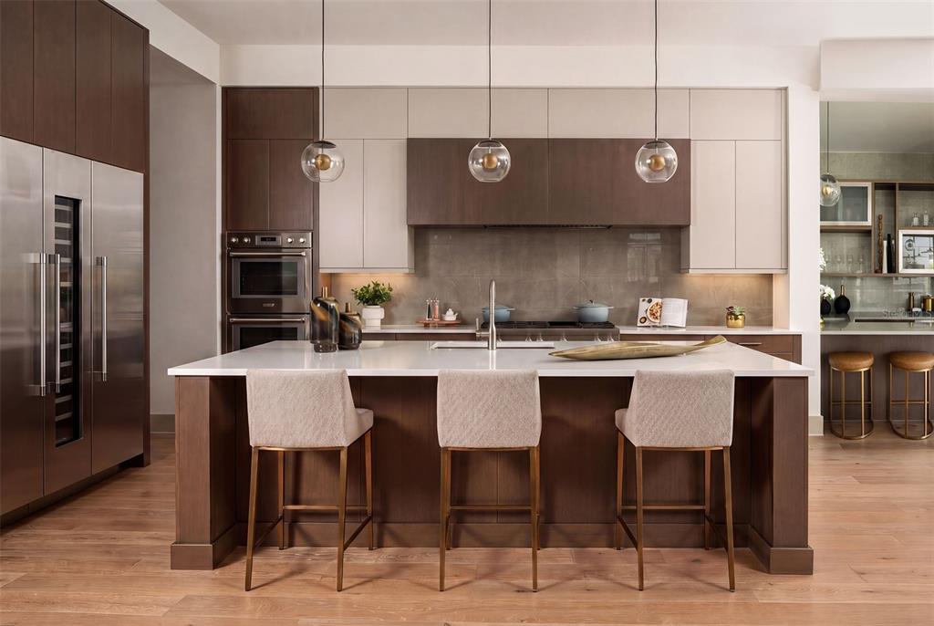 A modern kitchen features a large island with three stools, two-tone cabinetry, and stainless appliances — 263 CRYSTAL WATERS DRIVE, SARASOTA, FL