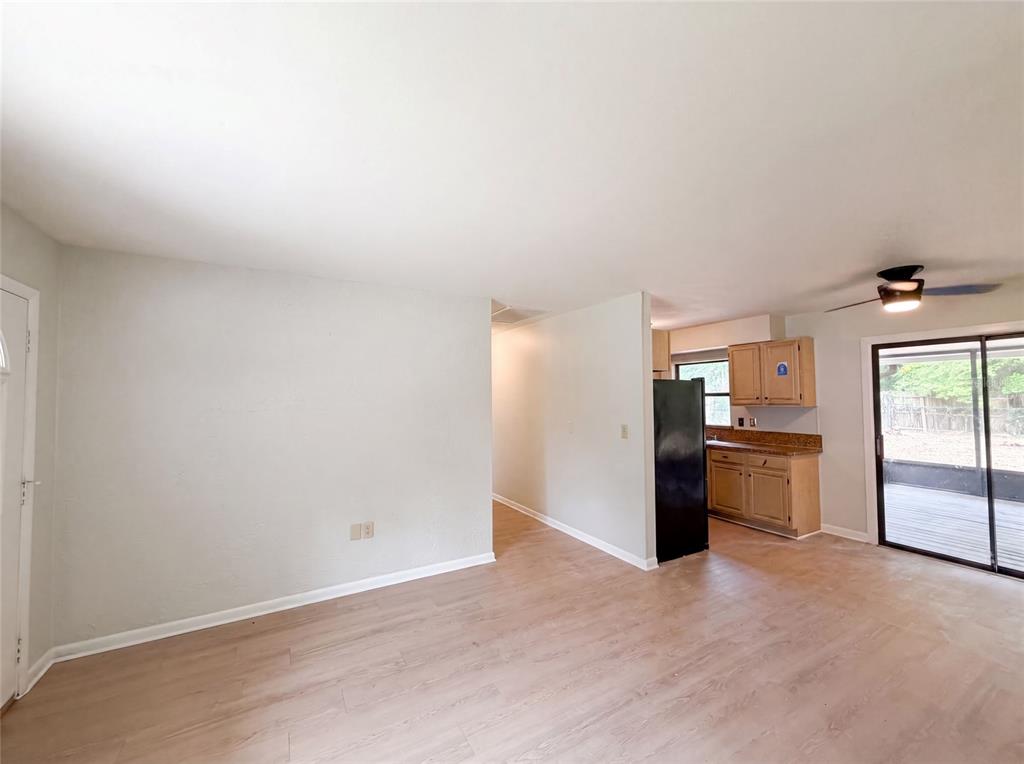 An interior view shows a living area with light wood flooring leading to a kitchen — 2630 SE 8TH AVENUE, OCALA, FL