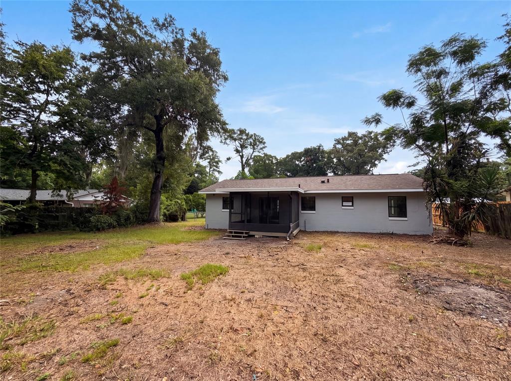 The exterior of a gray single-story house features a screened-in porch and a large yard — 2630 SE 8TH AVENUE, OCALA, FL