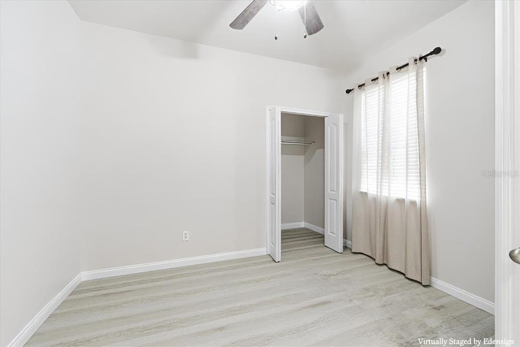 An empty bedroom features light-colored wood-look flooring, white walls, a ceiling fan, and a closet — 10591 HERON HIDEAWAY LOOP, LAND O LAKES, FL