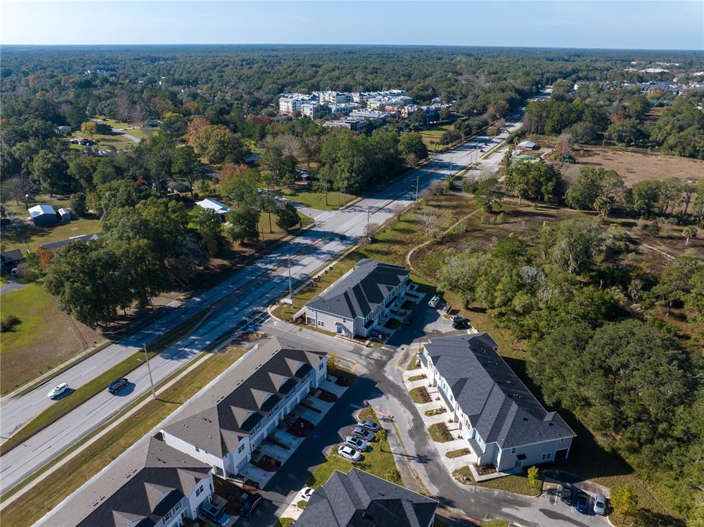 An aerial view shows several modern townhomes situated next to a multi-lane road and trees — 704 NW 126TH TERRACE, NEWBERRY, FL