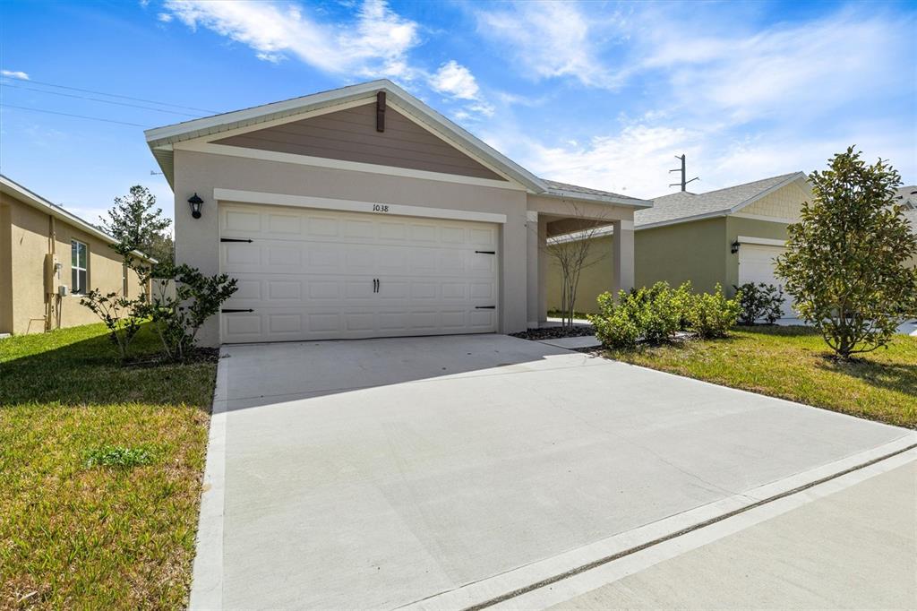 A single-story house with a beige stucco exterior, a two-car garage, and a concrete driveway — 1038 VICTORIA PARC AVENUE, ORANGE CITY, FL