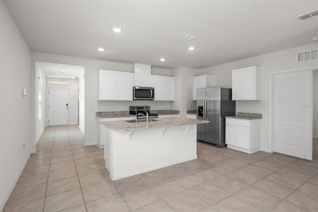 A kitchen with white cabinets, granite countertops, a center island, and stainless steel appliances — 1038 VICTORIA PARC AVENUE, ORANGE CITY, FL
