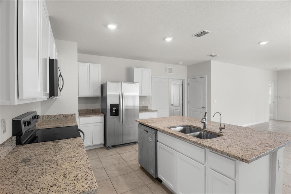 A kitchen features white cabinets, granite countertops, stainless steel appliances, and a central island — 1038 VICTORIA PARC AVENUE, ORANGE CITY, FL