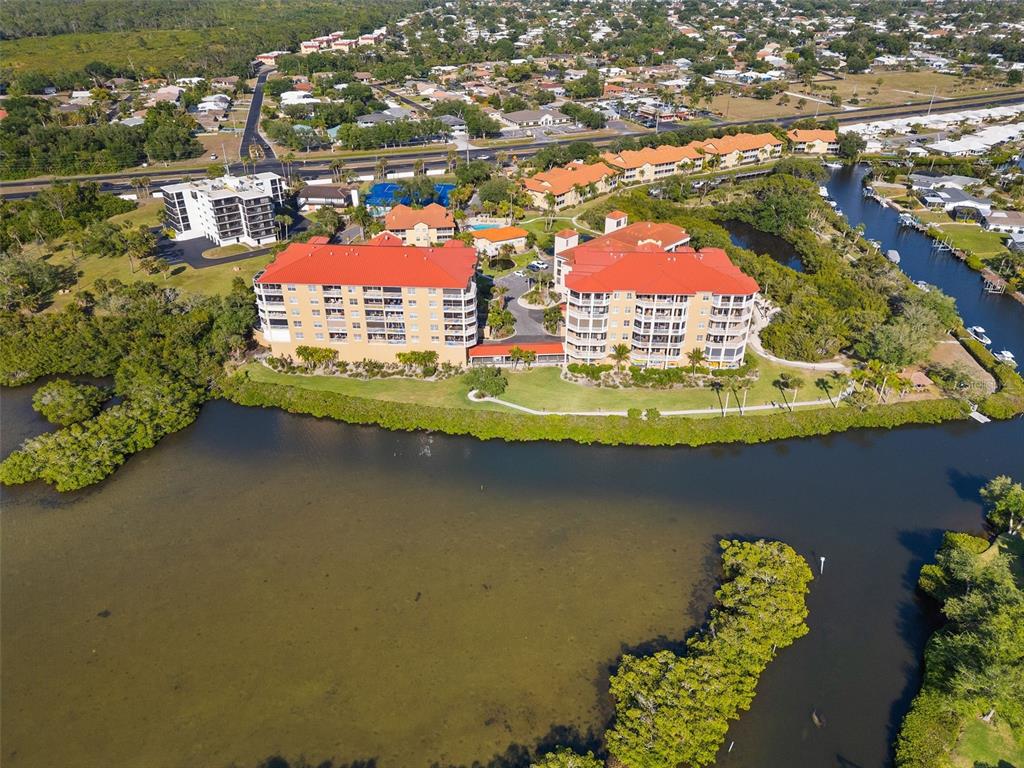 An aerial view shows two large residential buildings situated along a waterfront with mangrove vegetation — 6100 JESSIE HARBOR DRIVE UNIT 202, OSPREY, FL