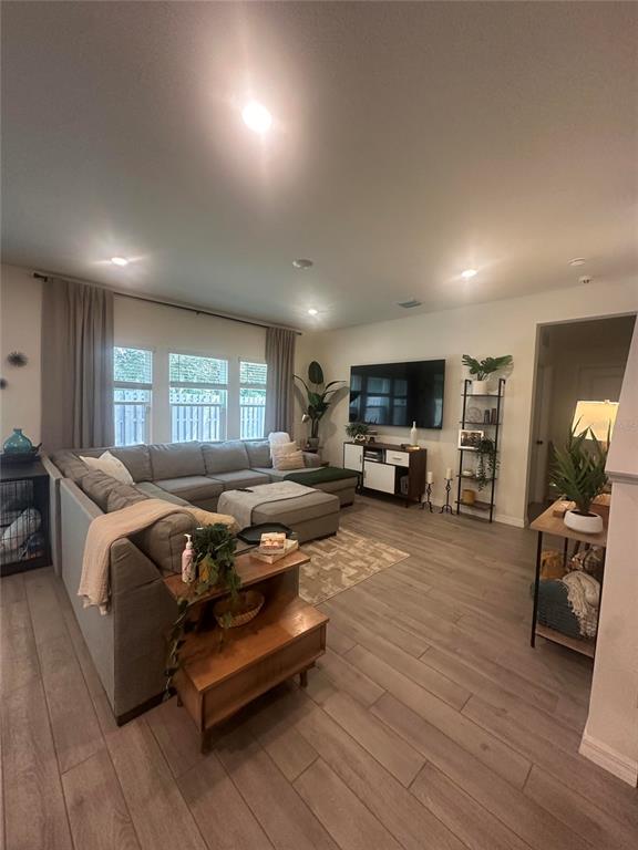 A living room features a large sectional sofa, a wall-mounted television, and wood-look flooring — 1169 NW 133RD WAY, NEWBERRY, FL