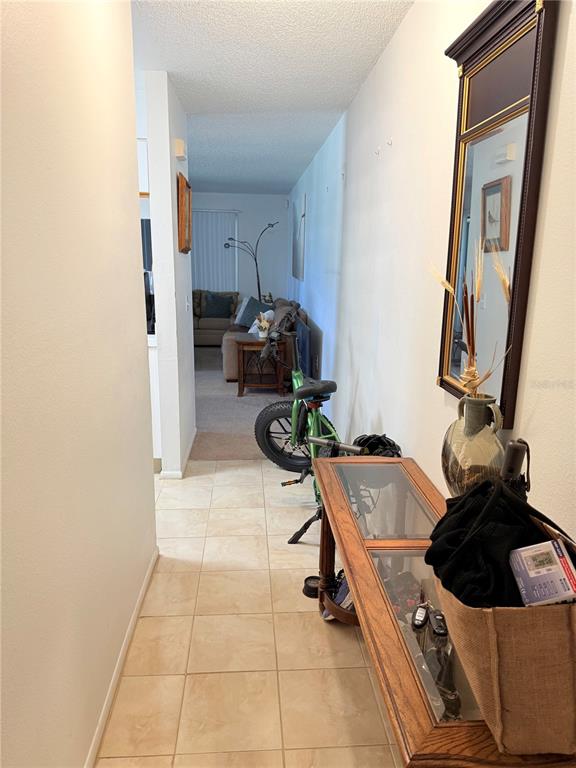 A tiled entryway leads into a living room featuring a bicycle and a wooden console table — 3001 58TH AVENUE S UNIT 1002, ST PETERSBURG, FL