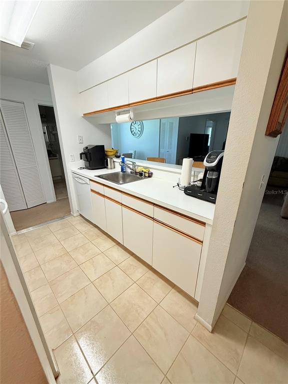 A kitchen features white cabinets, a stainless steel sink, and light-colored tile flooring — 3001 58TH AVENUE S UNIT 1002, ST PETERSBURG, FL