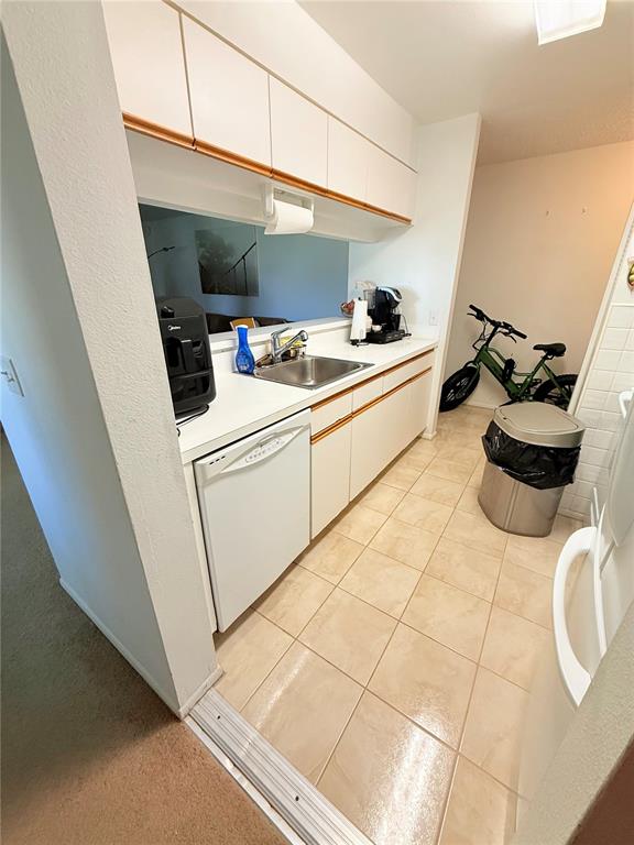 A kitchen features white cabinets, a dishwasher, a sink, and a bicycle parked nearby — 3001 58TH AVENUE S UNIT 1002, ST PETERSBURG, FL