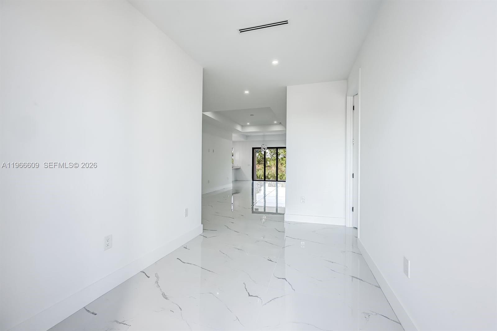 A bright hallway with white walls and polished marble-look tile flooring leads to a doorway — 865 Chipley ST E, Lehigh Acres FL 33974, LEHIGH ACRES, FL
