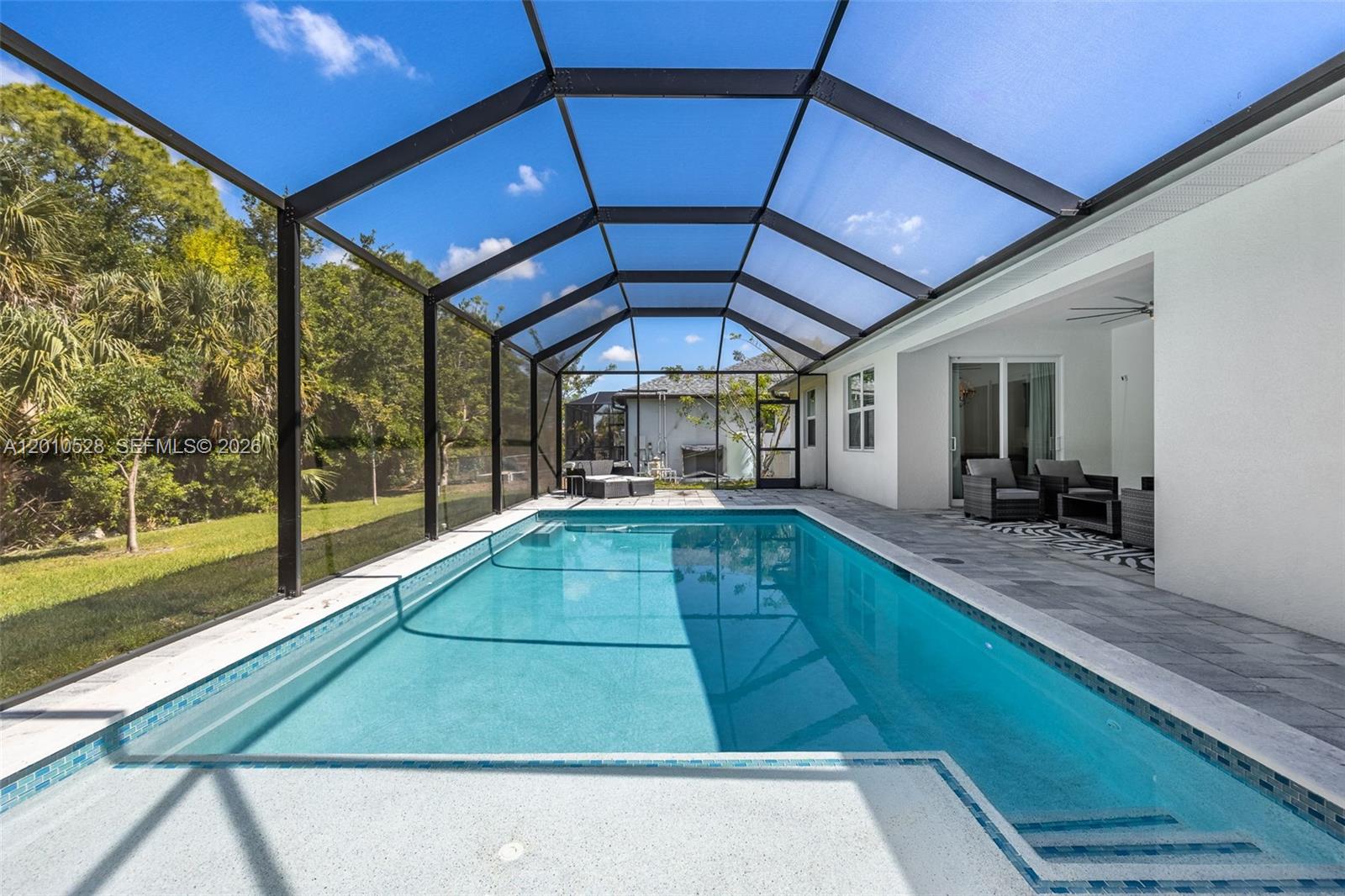 A rectangular swimming pool is enclosed by a screened lanai with a paved patio area — 1746 NW 26th AVE, Cape Coral FL 33993, CAPE CORAL, FL