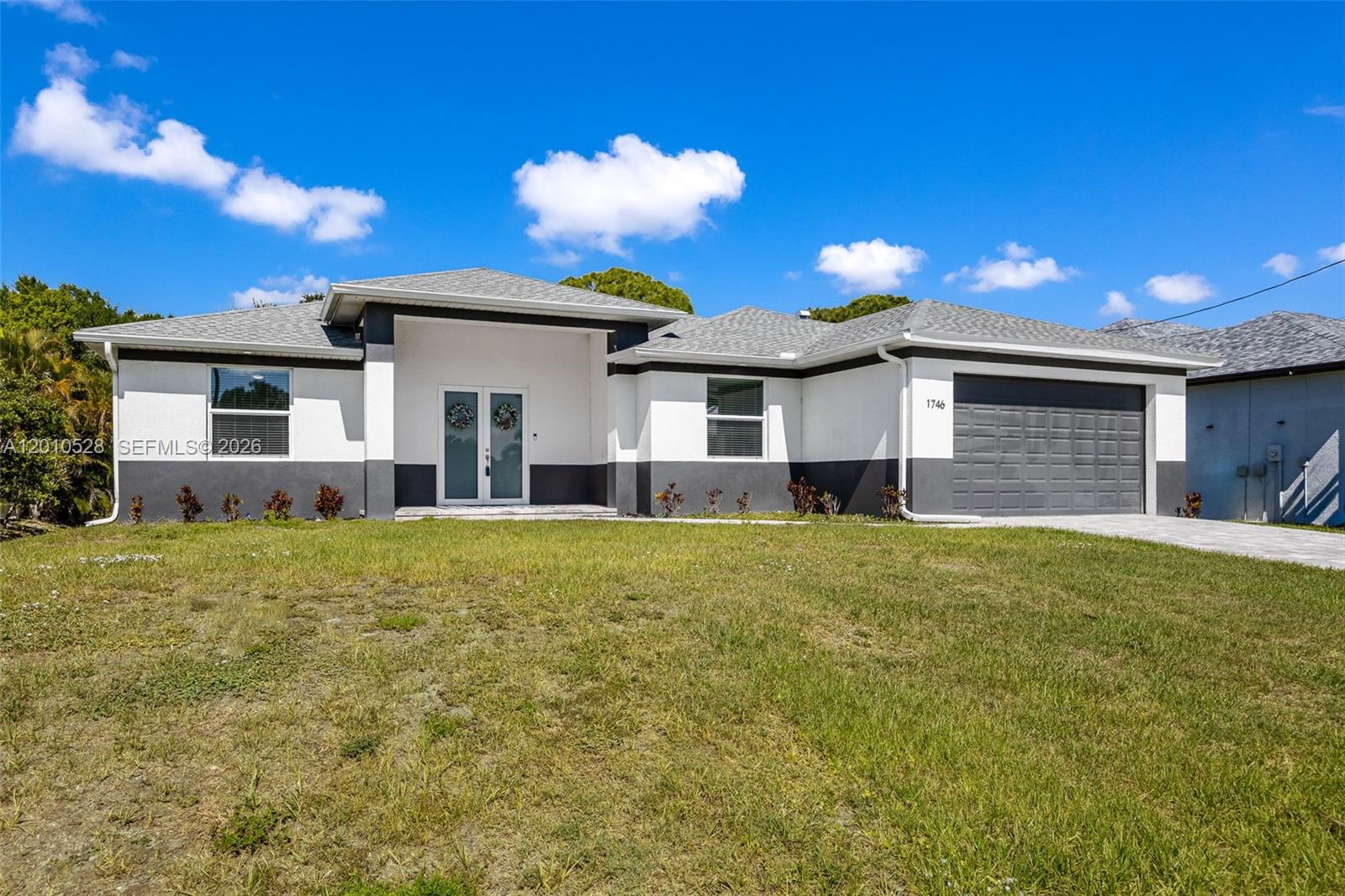 A single-story house with a white and gray exterior, a two-car garage, and a lawn — 1746 NW 26th AVE, Cape Coral FL 33993, CAPE CORAL, FL