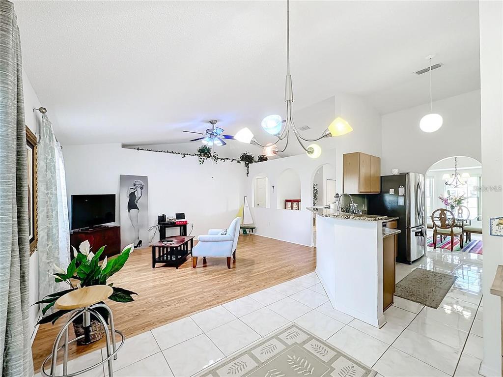 An open-concept living room and kitchen area with light wood flooring and white tile — 121 POMPEI DRIVE, KISSIMMEE, FL