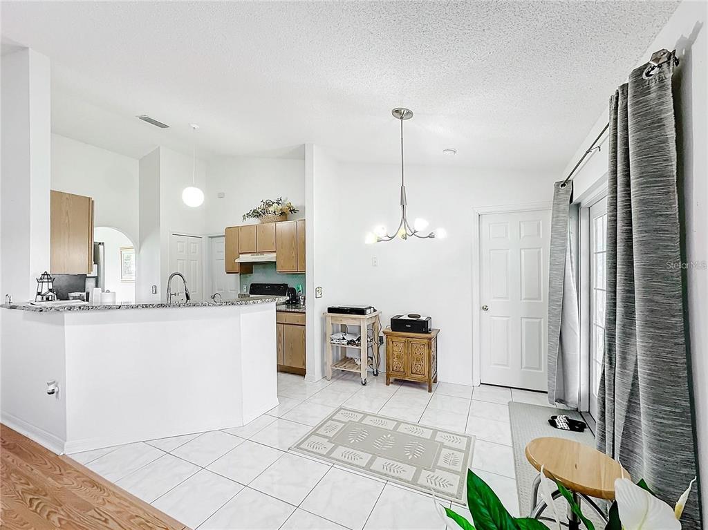 A kitchen with light wood cabinets and a breakfast bar opens into a tiled dining area — 121 POMPEI DRIVE, KISSIMMEE, FL