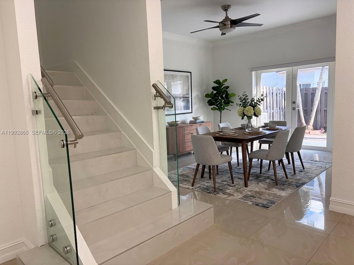 A staircase with a glass railing sits beside a dining area with a wooden table — 14738 SW 22nd Ter, Miami FL 33185, MIAMI, FL