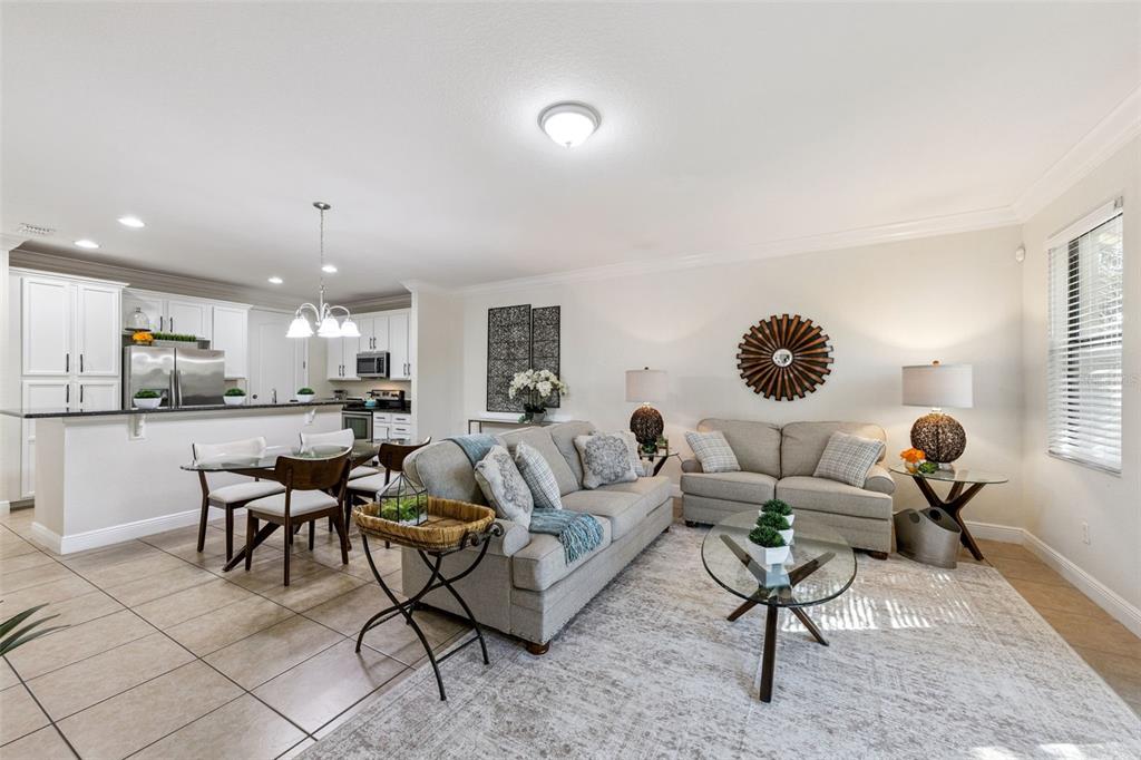 A living room with a sofa and loveseat opens to a kitchen with white cabinets — 8410 KELSALL DRIVE, ORLANDO, FL