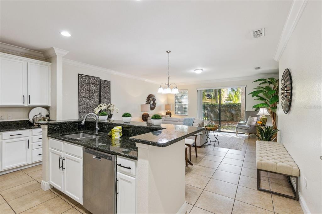 A kitchen with dark granite countertops and white cabinets opens into a living area — 8410 KELSALL DRIVE, ORLANDO, FL